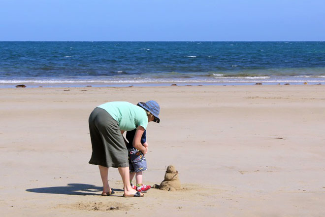 Lady and her son saying hello to George the sand snowman.