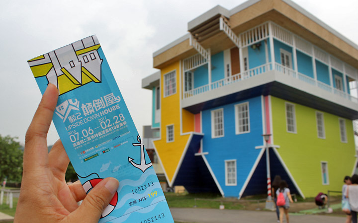 Upside down house in background, ticket in the foreground.